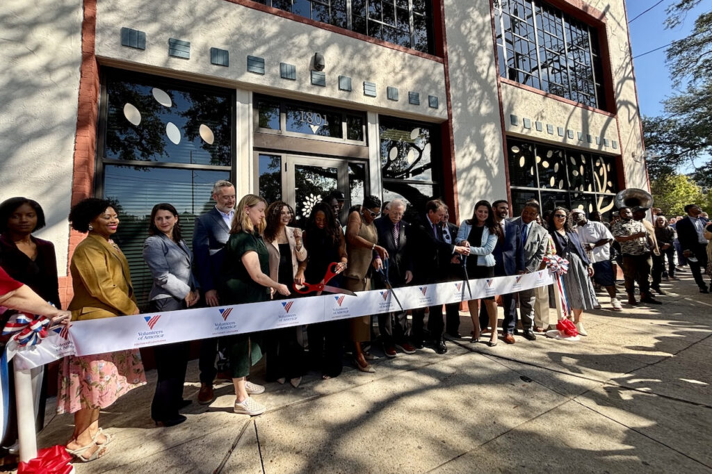 people standing in front of building cutting ribbon